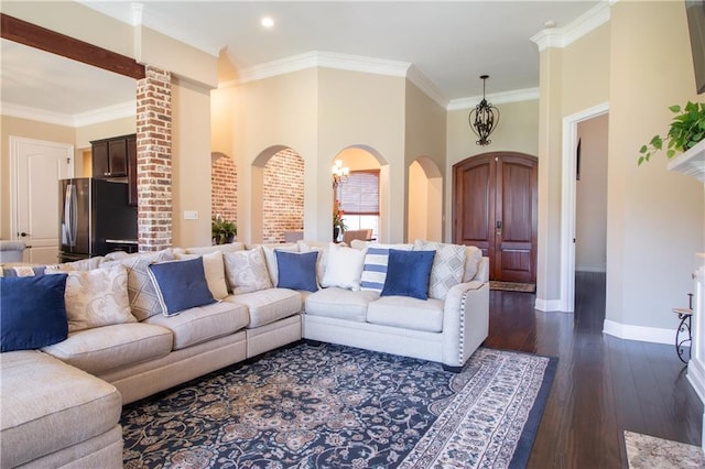 living room featuring a chandelier, dark wood-type flooring, and ornamental molding