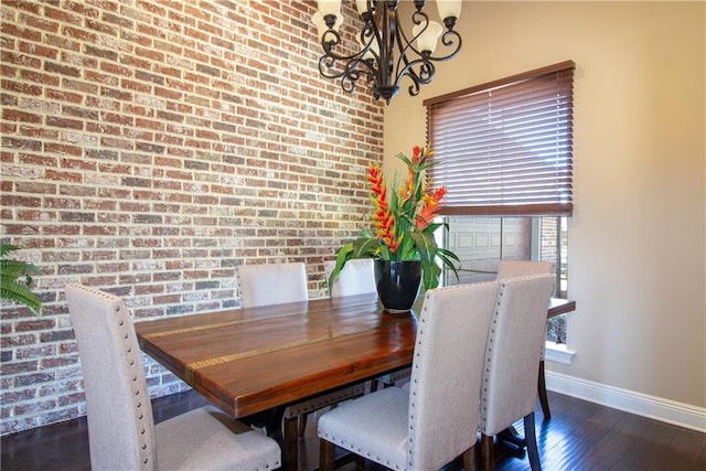 dining area featuring a notable chandelier, brick wall, and dark hardwood / wood-style floors