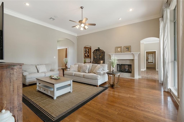 living room with a fireplace, ceiling fan, crown molding, and light hardwood / wood-style floors