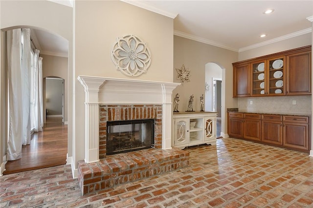 unfurnished living room featuring crown molding and a brick fireplace