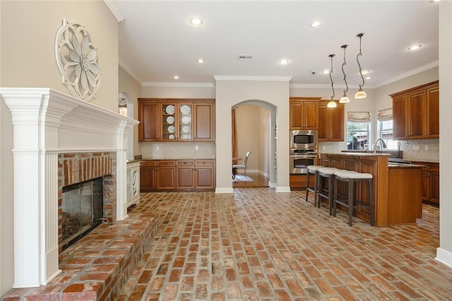 kitchen with a kitchen island, appliances with stainless steel finishes, crown molding, a breakfast bar area, and decorative backsplash