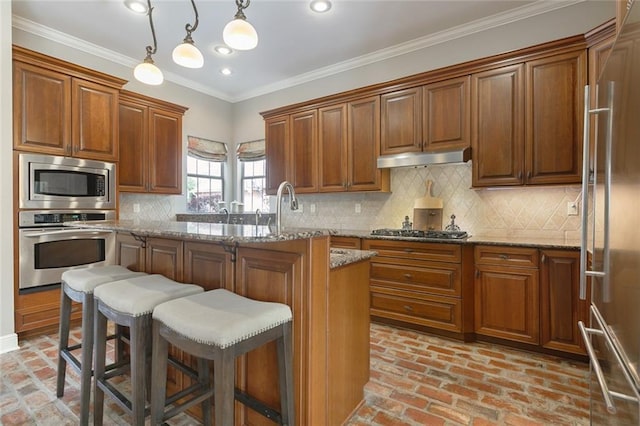 kitchen featuring appliances with stainless steel finishes, light stone counters, and pendant lighting