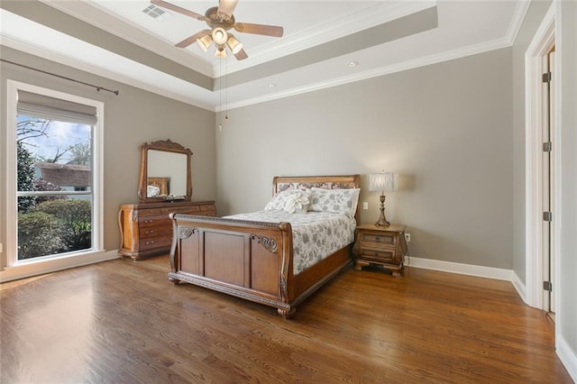 bedroom featuring crown molding, a tray ceiling, dark hardwood / wood-style floors, and ceiling fan