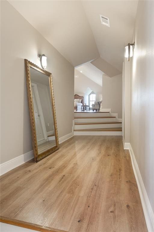 bonus room with light wood-type flooring and vaulted ceiling