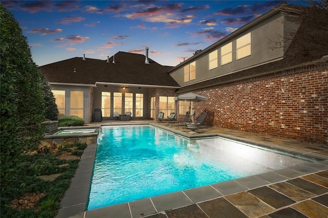 pool at dusk with a patio area