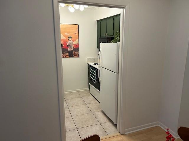 kitchen featuring white appliances, light countertops, baseboards, and light tile patterned floors