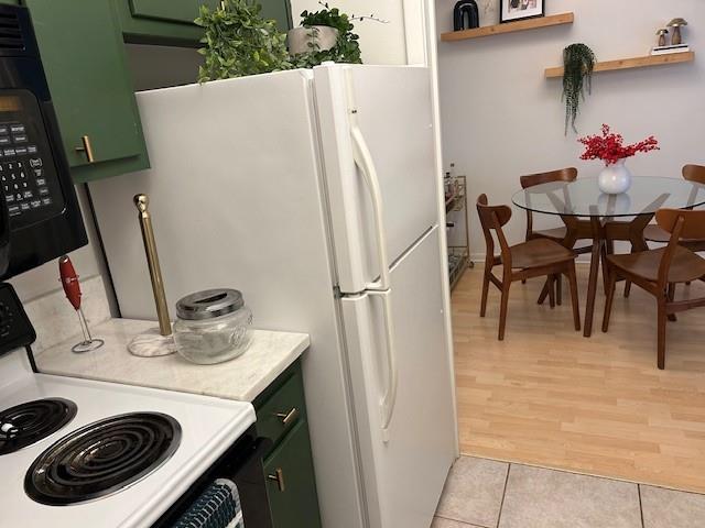 4007 St Charles Ave Unit 319, New Orleans, LA 70115 - kitchen with white appliances, green cabinetry, light countertops, and light tile patterned floors