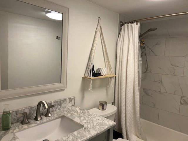 full bath with toilet, shower / bath combo with shower curtain, and vanity