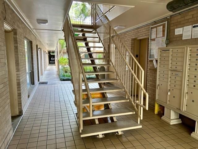 4007 St Charles Ave Unit 319, New Orleans, LA 70115 - staircase featuring brick wall, healthy amount of natural light, and tile patterned flooring