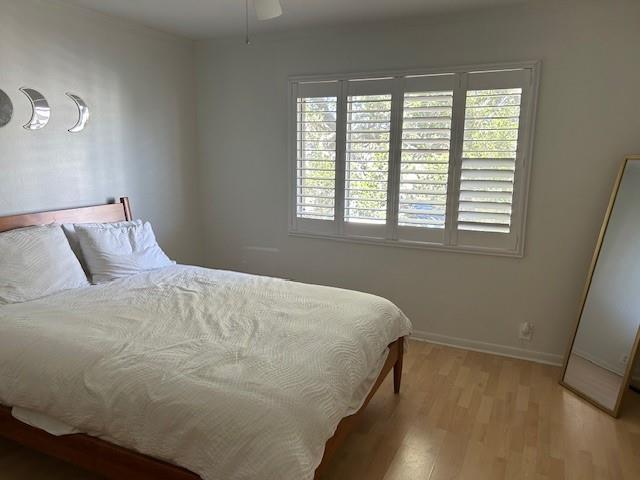 bedroom featuring light wood-style floors, baseboards, and a ceiling fan