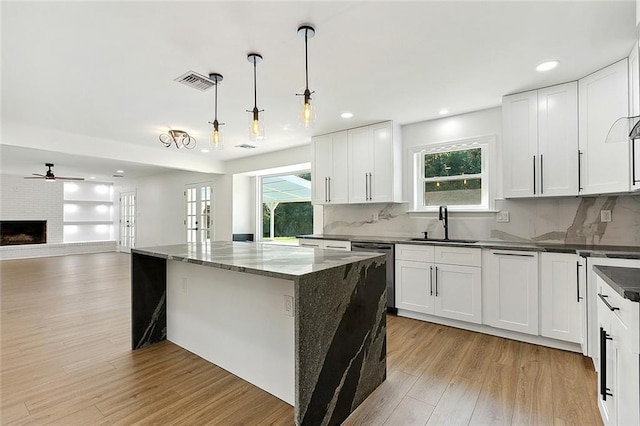 kitchen featuring visible vents, dishwasher, light wood-style flooring, open floor plan, and a sink