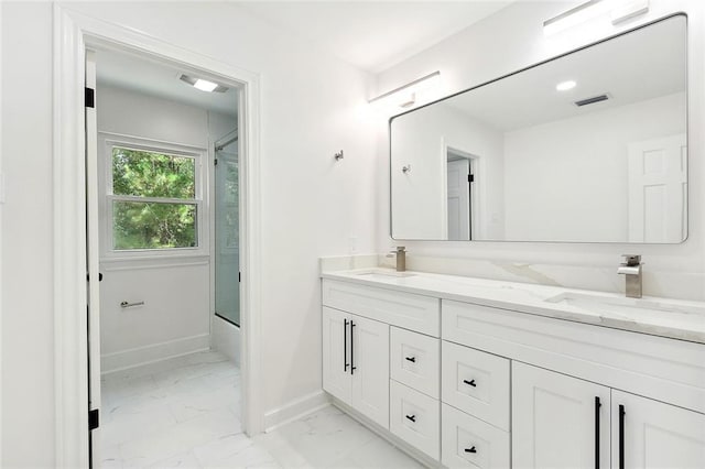 full bath with marble finish floor, a sink, baseboards, and double vanity