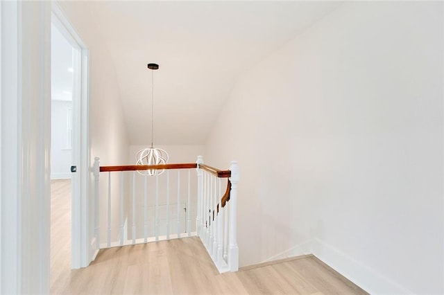 stairs with a chandelier, wood finished floors, and baseboards