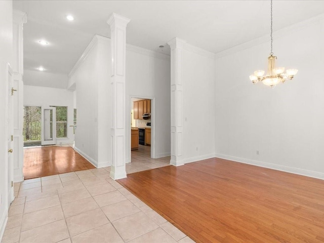 interior space featuring ornamental molding, light tile patterned flooring, a chandelier, and ornate columns