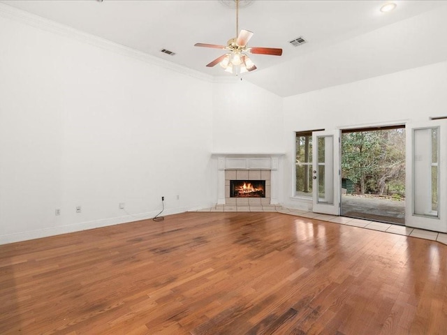 unfurnished living room featuring a fireplace, ornamental molding, vaulted ceiling, ceiling fan, and hardwood / wood-style floors