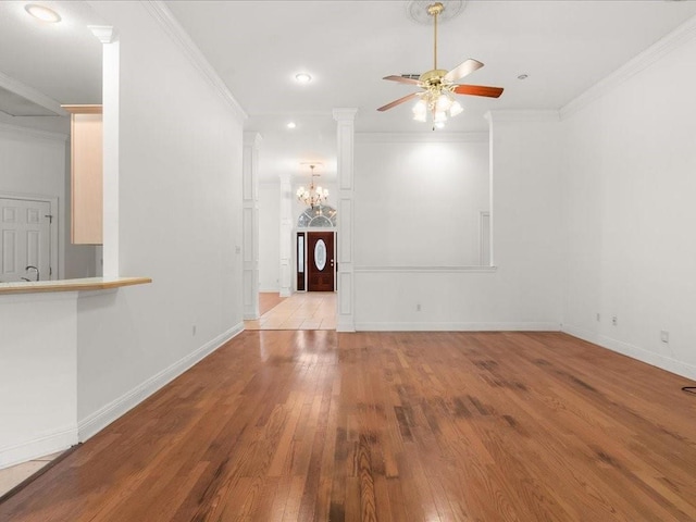 unfurnished living room with ceiling fan with notable chandelier, light wood-type flooring, crown molding, and ornate columns