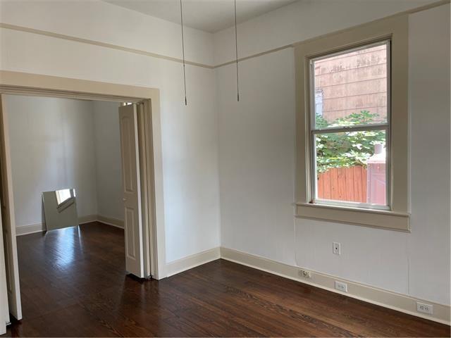 empty room featuring a healthy amount of sunlight, baseboards, and dark wood-type flooring