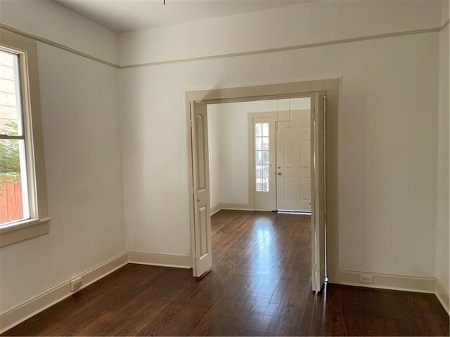 foyer with dark wood-style flooring and baseboards