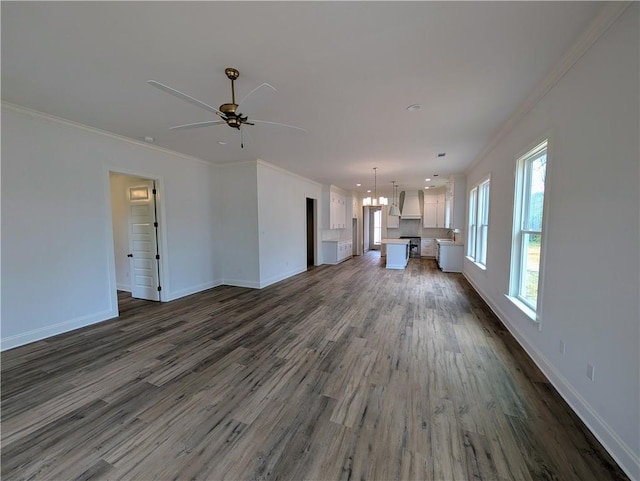 unfurnished living room with ceiling fan with notable chandelier, dark hardwood / wood-style flooring, and ornamental molding