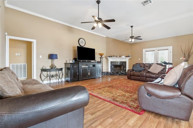 living room featuring a premium fireplace, ornamental molding, light wood-type flooring, and lofted ceiling