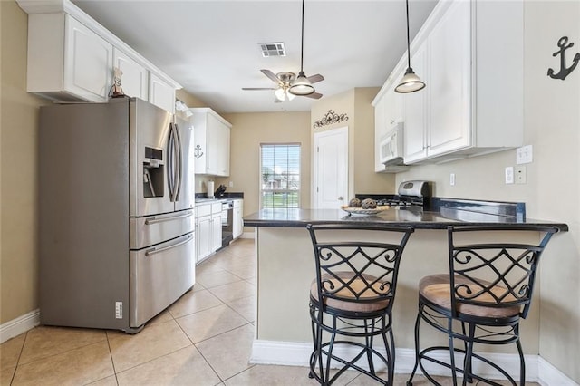 kitchen with white cabinets, a kitchen bar, stainless steel fridge, and kitchen peninsula