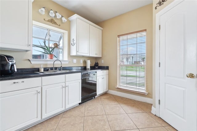 kitchen featuring plenty of natural light, white cabinetry, light tile patterned floors, sink, and black dishwasher