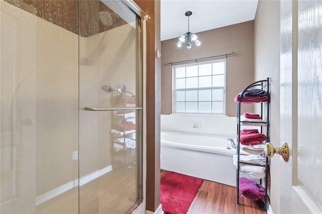 bathroom with hardwood / wood-style flooring, plus walk in shower, and an inviting chandelier