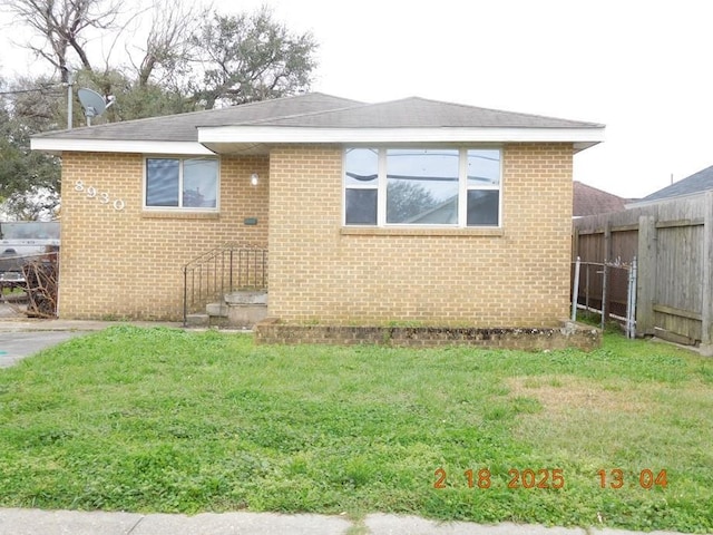 exterior space with a front yard, fence, and brick siding