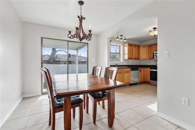 dining area featuring track lighting, light tile patterned floors, baseboards, and an inviting chandelier