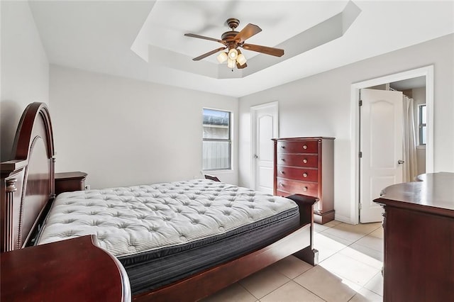 tiled bedroom featuring a raised ceiling and ceiling fan