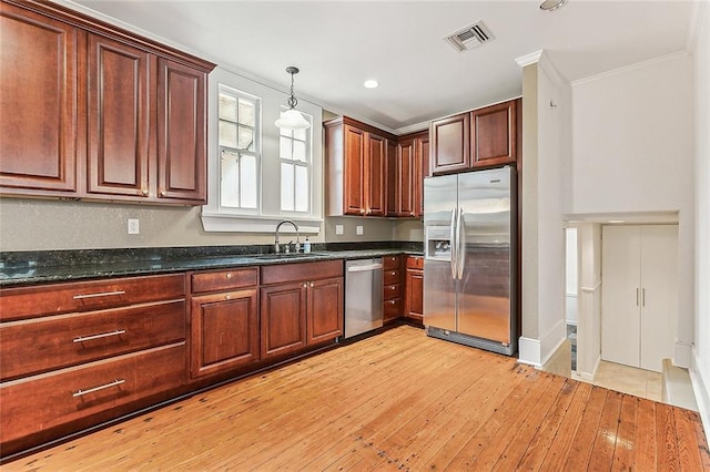 kitchen featuring hanging light fixtures, stainless steel appliances, light wood-type flooring, visible vents, and a sink