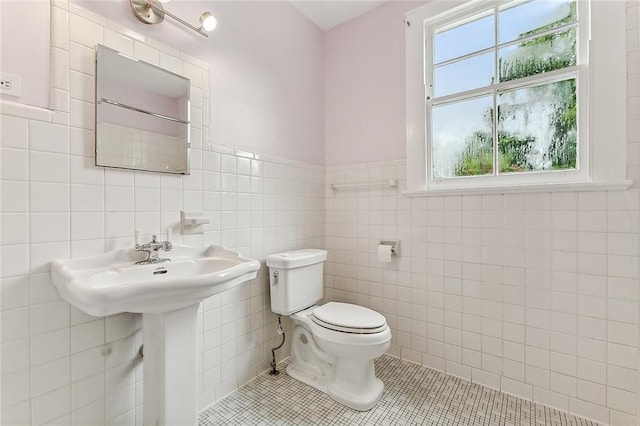 half bathroom with tile patterned floors, tile walls, and toilet