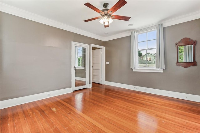 spare room featuring wood finished floors, baseboards, ornamental molding, and ceiling fan