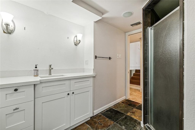 bathroom featuring an enclosed shower, stone tile floors, baseboards, vanity, and visible vents