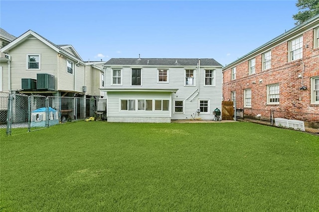 rear view of house with a fenced backyard, central AC, a residential view, and a lawn