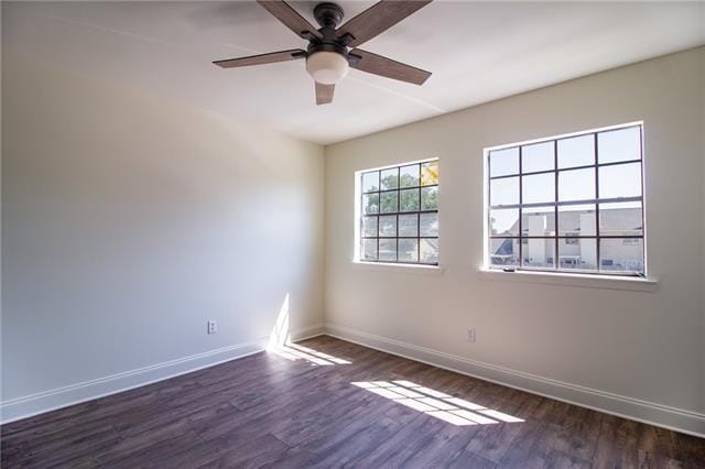 spare room featuring a ceiling fan, dark wood finished floors, and baseboards