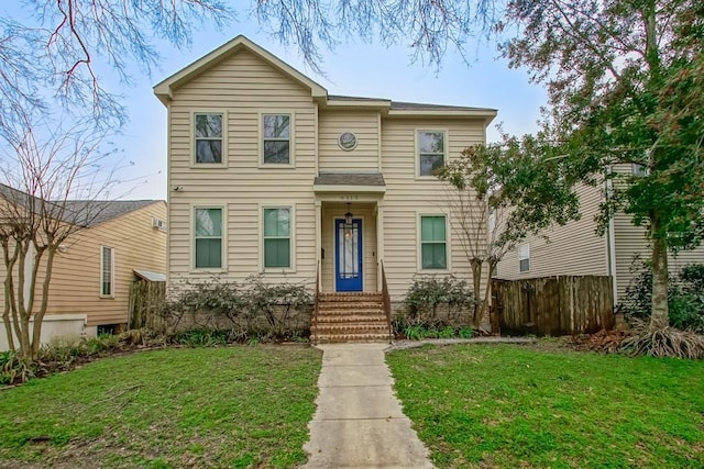 traditional-style home with a front yard and fence