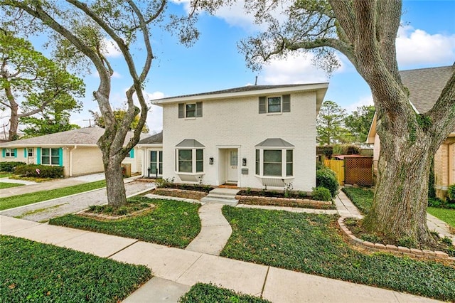 view of front of house featuring brick siding, fence, and a front yard