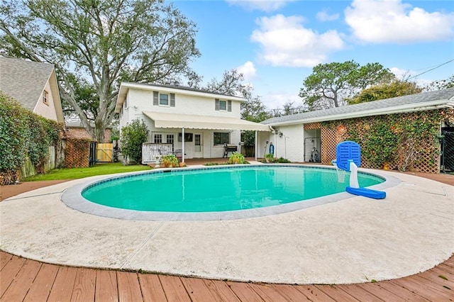 rear view of house with a wooden deck, fence private yard, and a fenced in pool