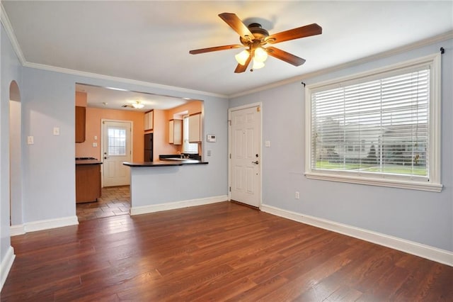 unfurnished living room featuring arched walkways, baseboards, dark wood-style floors, and crown molding