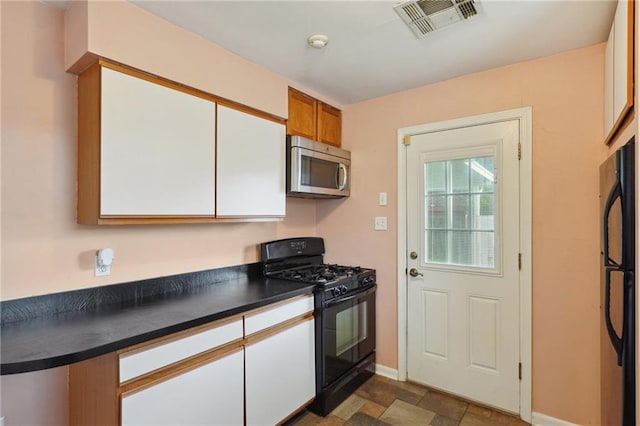 kitchen with dark countertops, black appliances, visible vents, and white cabinets