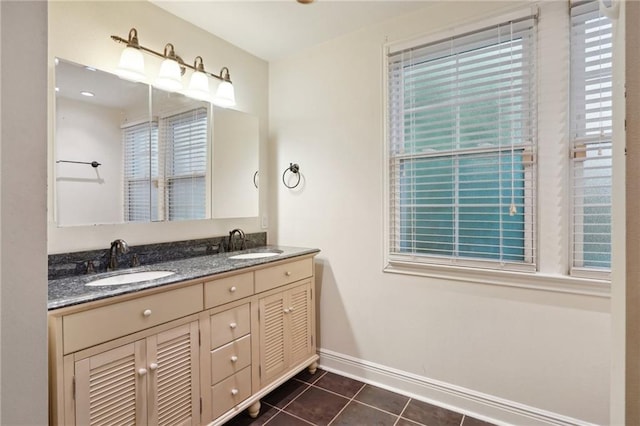 bathroom with baseboards, double vanity, a sink, and tile patterned floors