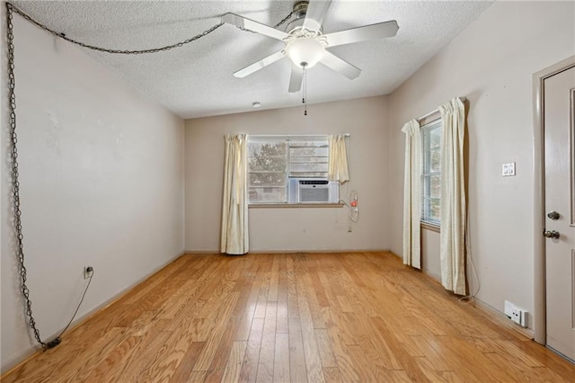 spare room featuring light wood-style floors, plenty of natural light, a textured ceiling, and cooling unit