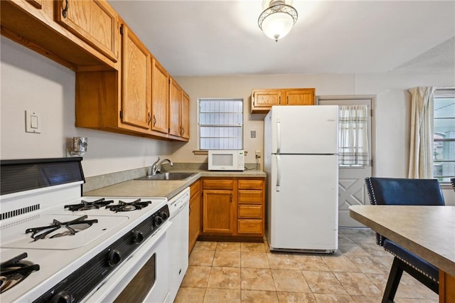 kitchen with light countertops, white appliances, a sink, and a wealth of natural light