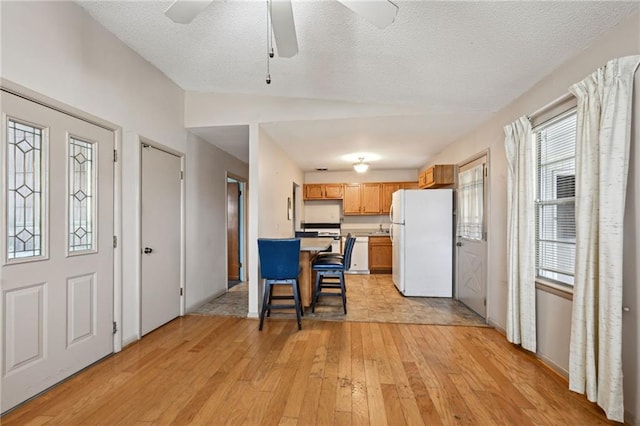 kitchen featuring a textured ceiling, a breakfast bar, light countertops, light wood-type flooring, and freestanding refrigerator