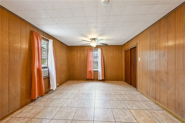 unfurnished room featuring light tile patterned floors, wooden walls, and a ceiling fan