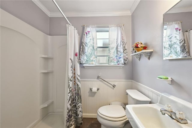 full bathroom featuring a wainscoted wall, crown molding, a sink, and a stall shower