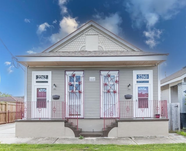 226062 N Roman St, New Orleans, LA 70117 - view of front of home featuring roof with shingles, a porch, and fence