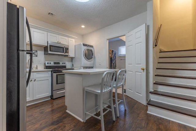 226062 N Roman St, New Orleans, LA 70117 - kitchen featuring stacked washer / drying machine, stainless steel appliances, white cabinets, and dark wood-style floors