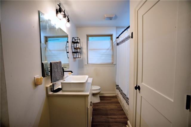 bathroom featuring a shower with curtain, toilet, wood finished floors, baseboards, and vanity